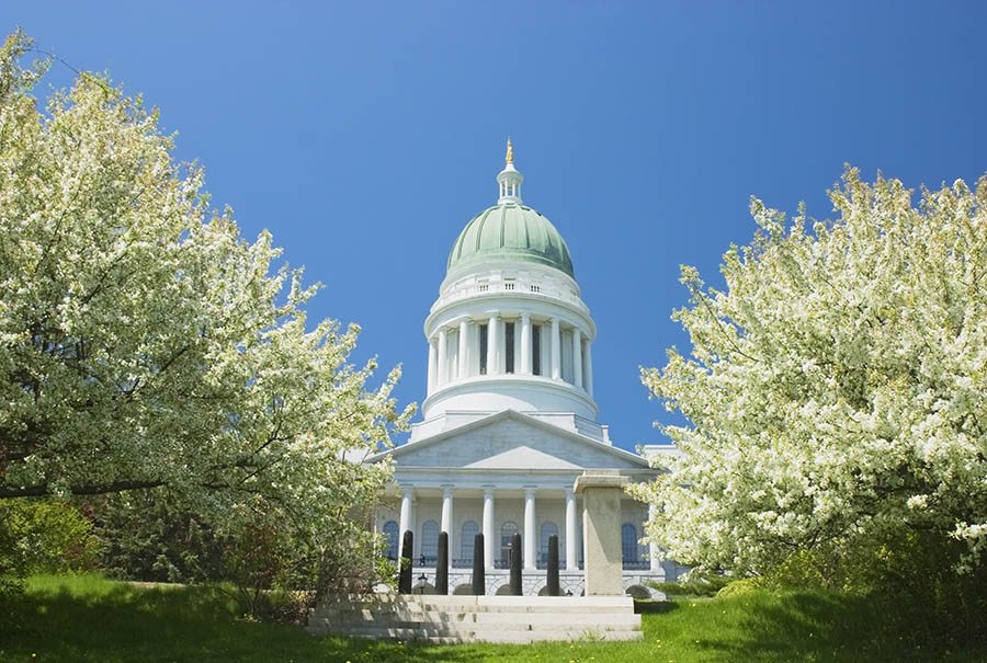 Maine capitol building with trees in foreground.