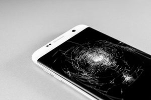 Close up of a mobile device with a cracked screen.