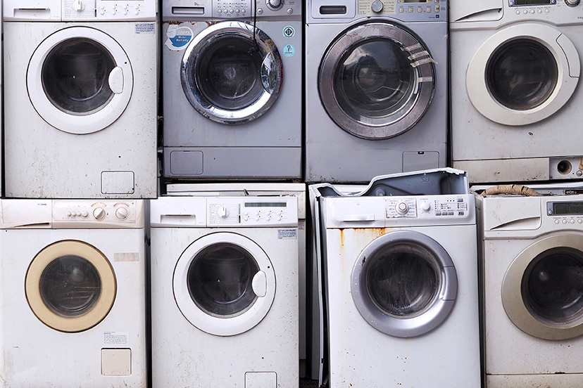 Old washing machines stacked for recycling.