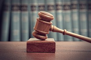 Close up of a judge's gavel with books in background.