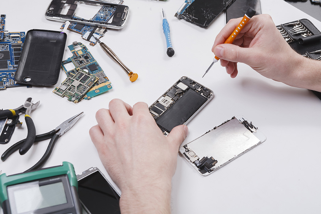 A worker repairs a mobile device.