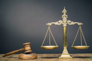 Table with a court gavel and scales with a dark background.