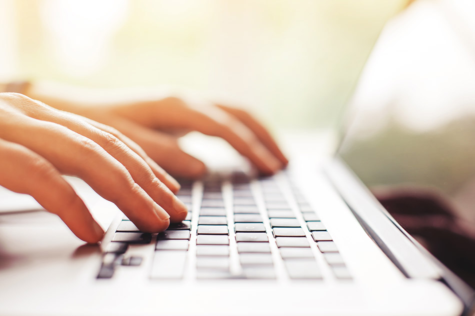 Hands typing on a laptop.