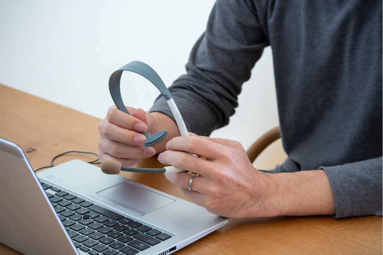 A person seated at a laptop with a headset.