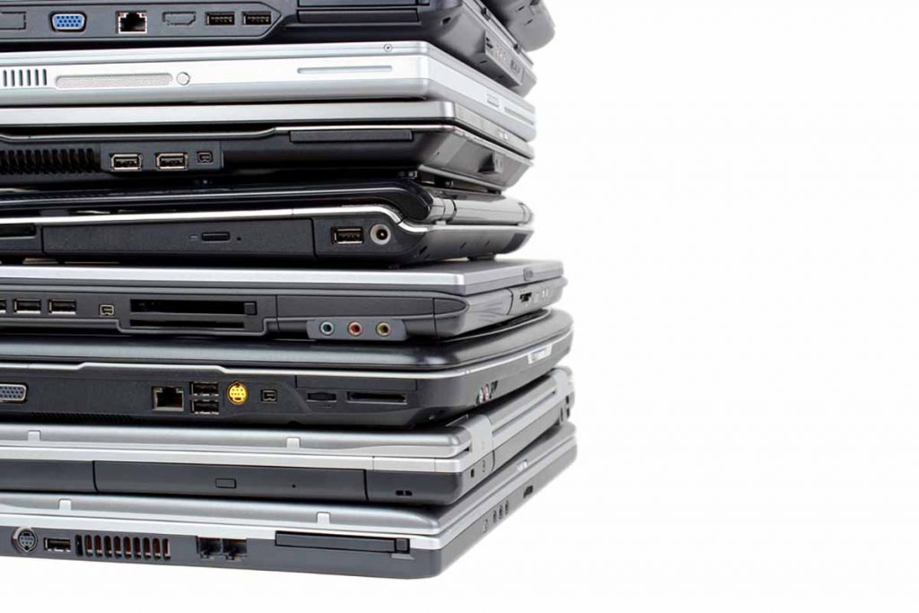 Stacked laptops for reuse and recycling against a white background.