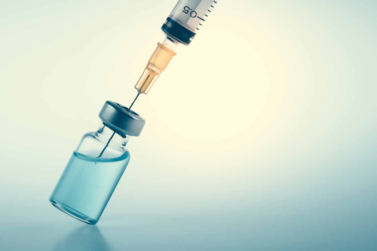 Close up of a syringe drawing from a vaccine vial.