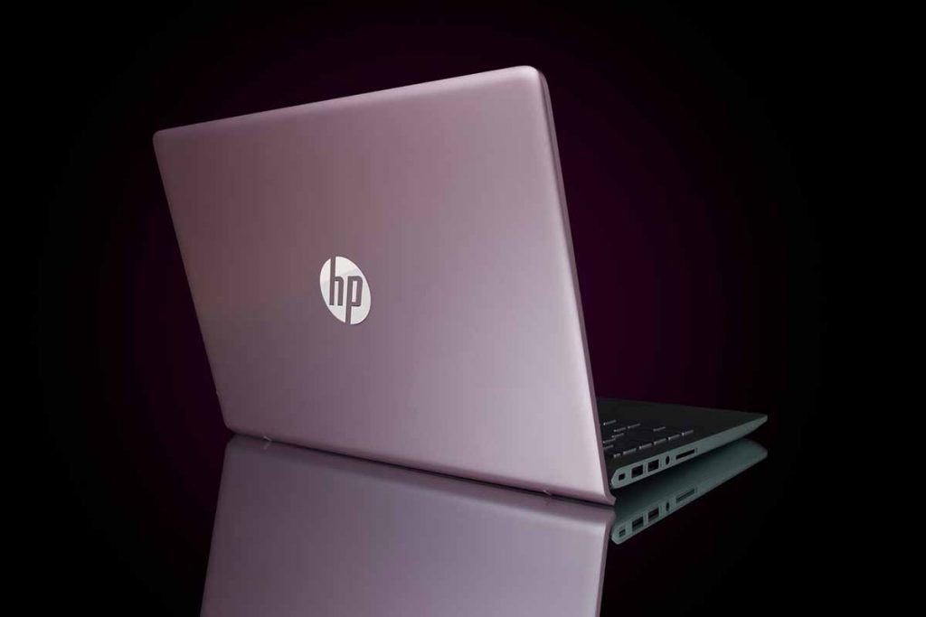 HP laptop on desk with black background.
