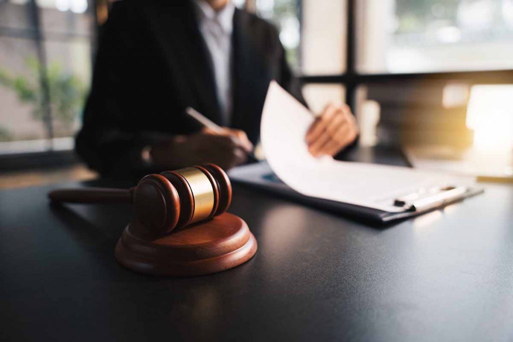 Lawyer with gavel, working on documents at desk.