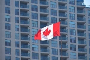 Canadian flag flying with building in background.