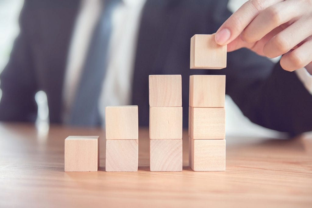 Person stacking blocks representing business growth.