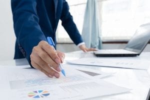 A person standing at a table with business documents and a computer.