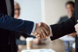 Two people in suits shake hands.