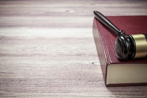 A gavel and book on a wooden desk.