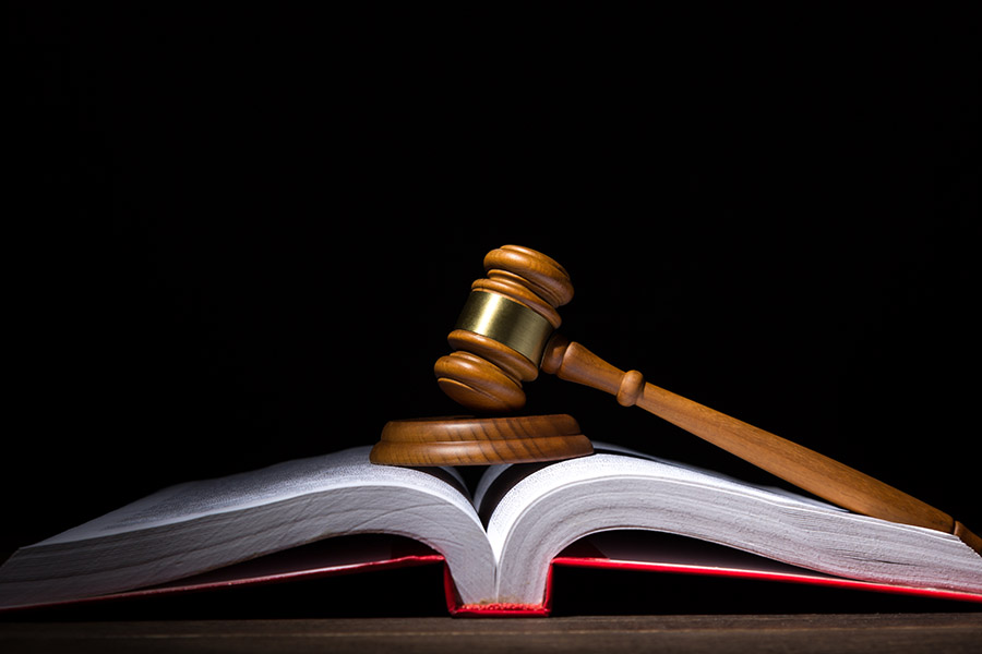 Court gavel rests on a book against a black background.