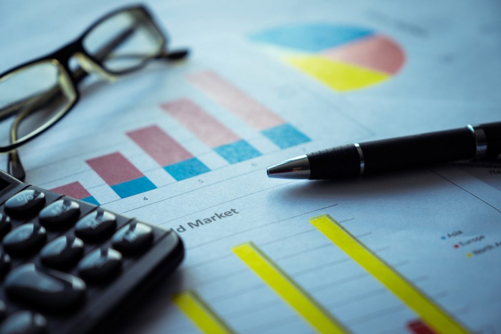 Business charts with pen, glasses and calculator.