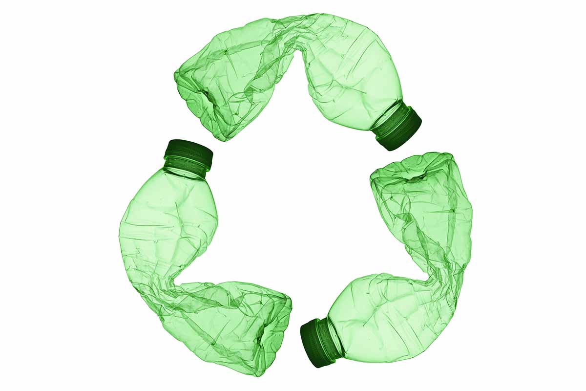 A recycle symbol made from three green plastic bottles.