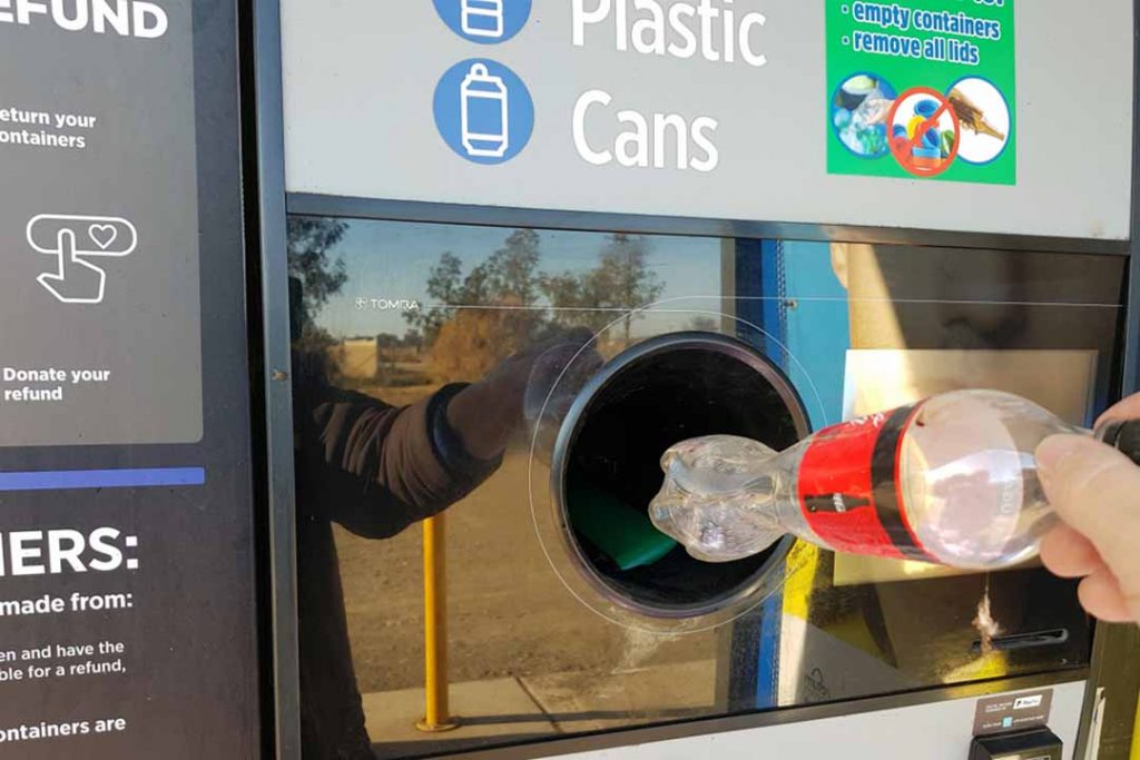 A person places a plastic bottle in a reverse vending machine.