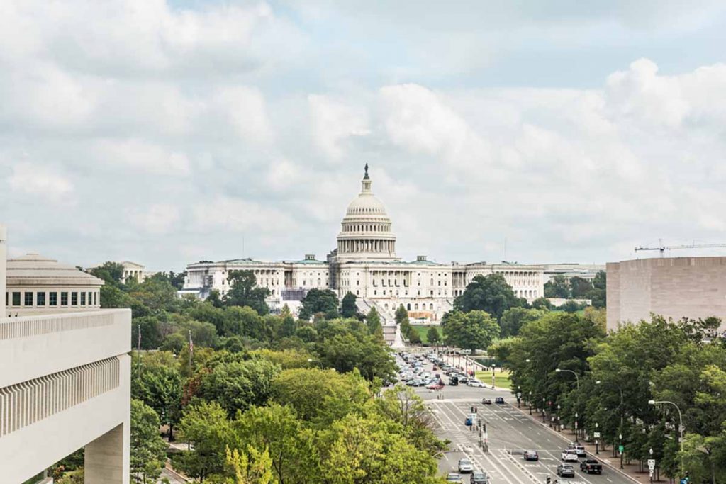 View of the U.S. capitol building in Washington, D.C. with trees and street activity.