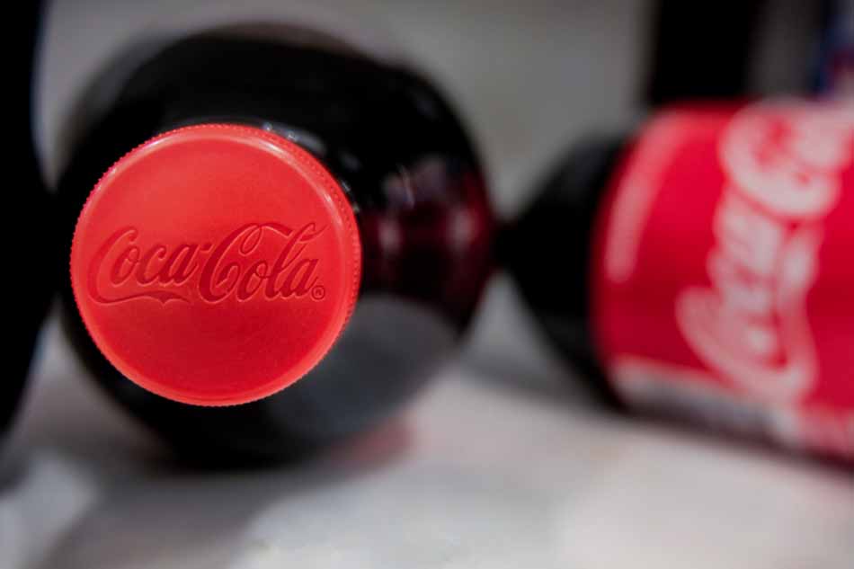 Bottles of Coca-Cola with focus on red cap with logo.