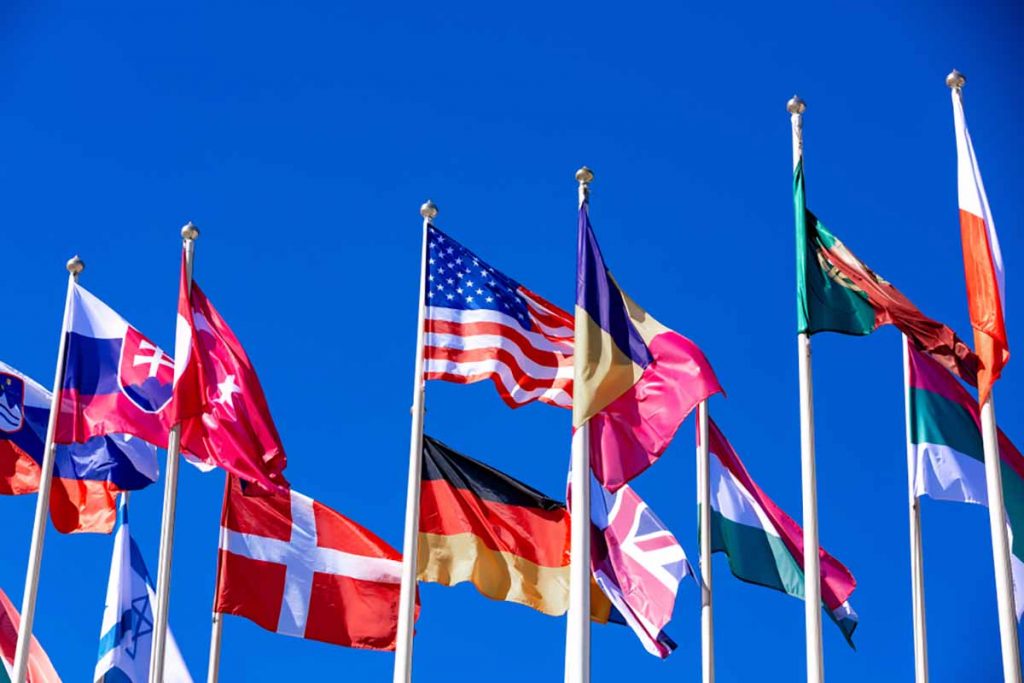Flags from various nations against a blue sky background.