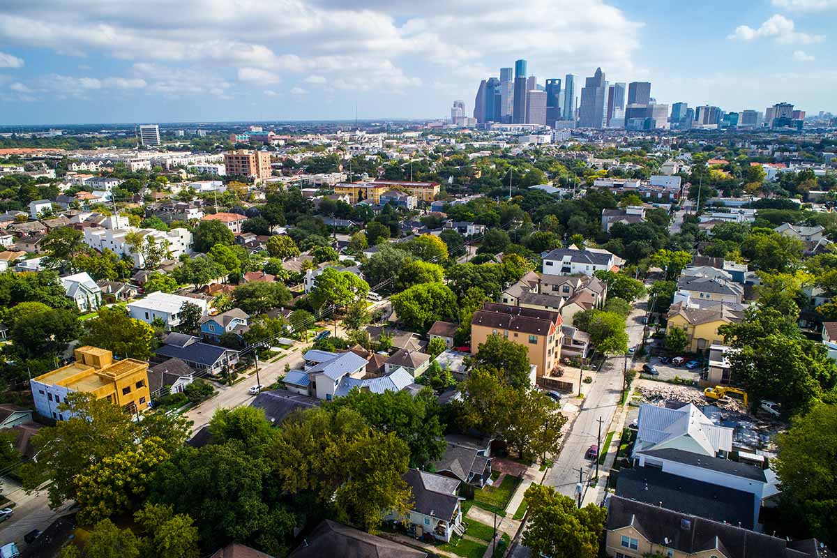 Aerial view of Houston neighborhood with downtown skyline in distance.