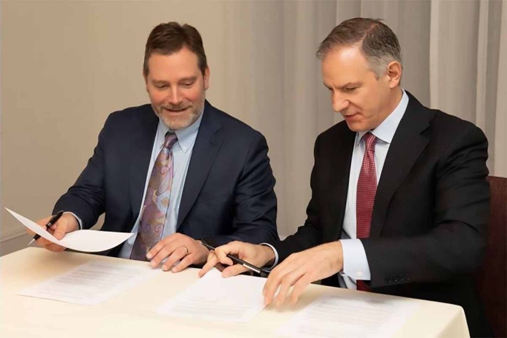 Amcor and ExxonMobil leaders sign an agreement.