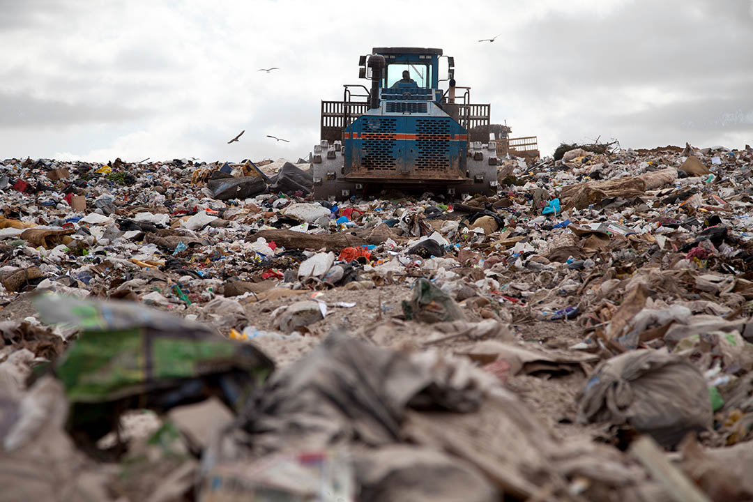 Landfill scene with machinery and material.