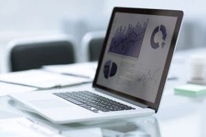 Laptop on table showing data charts.