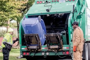 Workers unload a recycling cart into a truck.