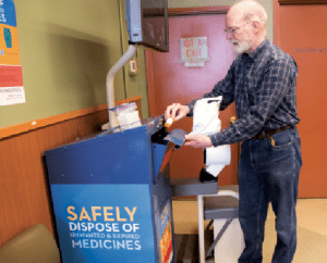 Man places medications into collection station for recycling.