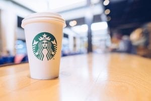 A Starbucks cup sits on a cafe table.