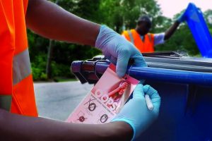 Worker places an "oops" tag placed on a curbside recycling bin.