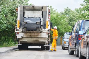 A worker collecting recycling into a truck.
