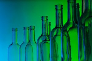 Glass bottles with a blue and green lit background.