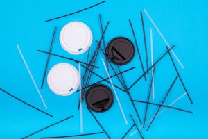 Coffee cup lids and straws on a blue background.