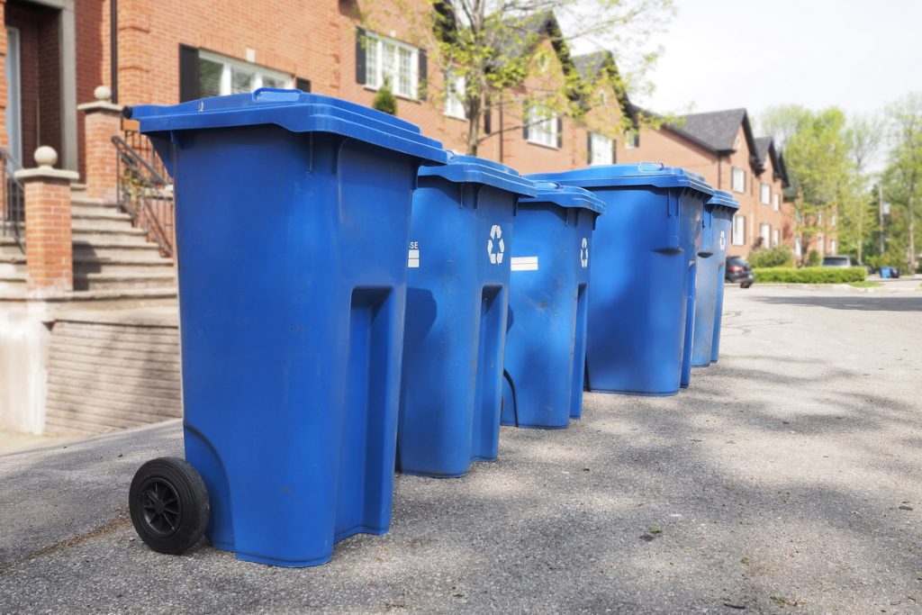 Curbside recycling carts in front of residential properties.