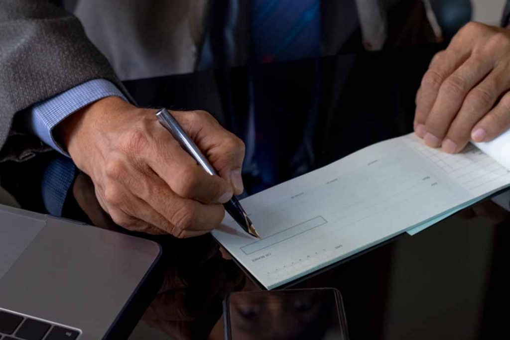 Person in a suit signing a check.