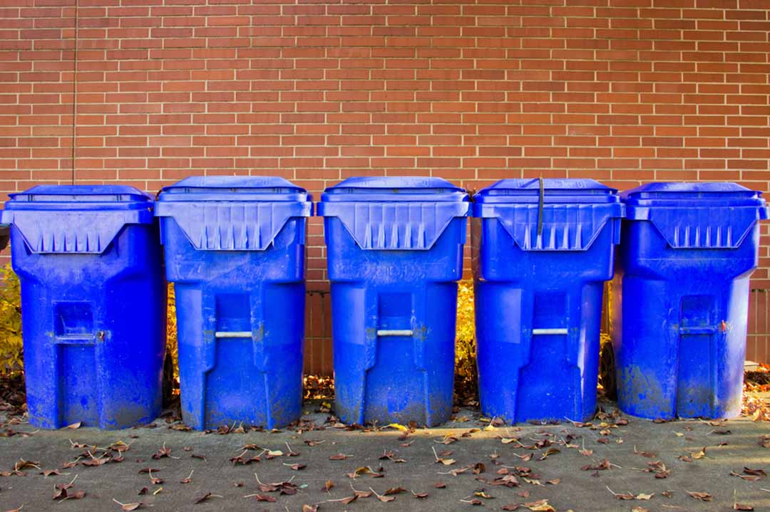 Recycling carts in front of a brick wall.