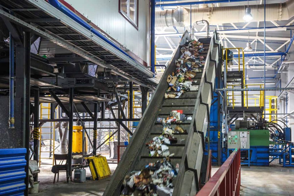 Materials on a conveyor inside a waste and recycling processing plant.