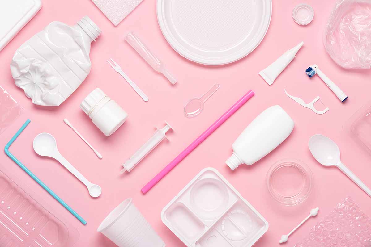 Various plastic items arranged on a pink background.