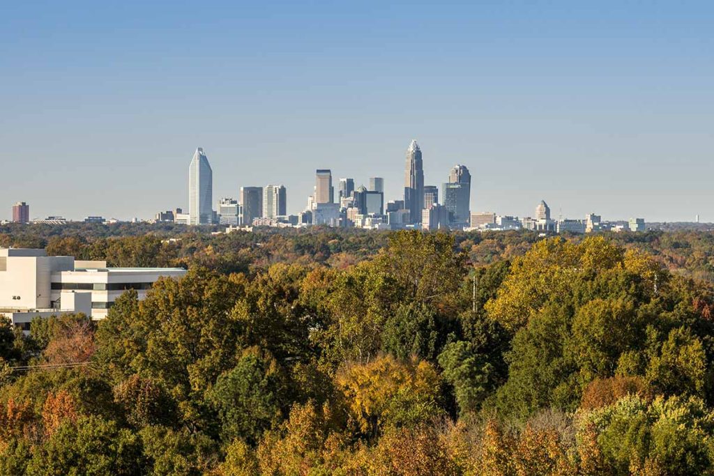 Charlotte, N.C. skyline seen in distance above trees.