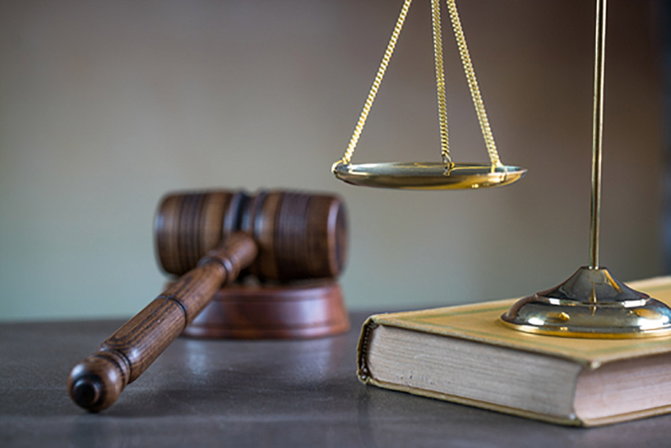 Court gavel with scales and book on desk.