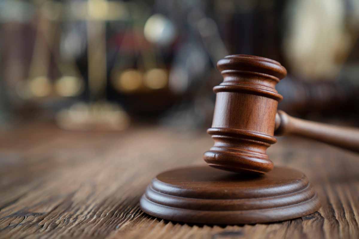 Court gavel resting on a wooden desk with blurred background.