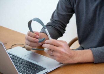 A person seated at a laptop with a headset.