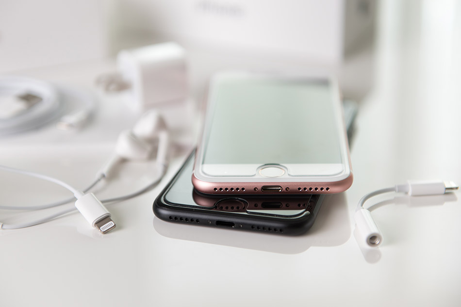 Two iPhones and accessories on a desk.
