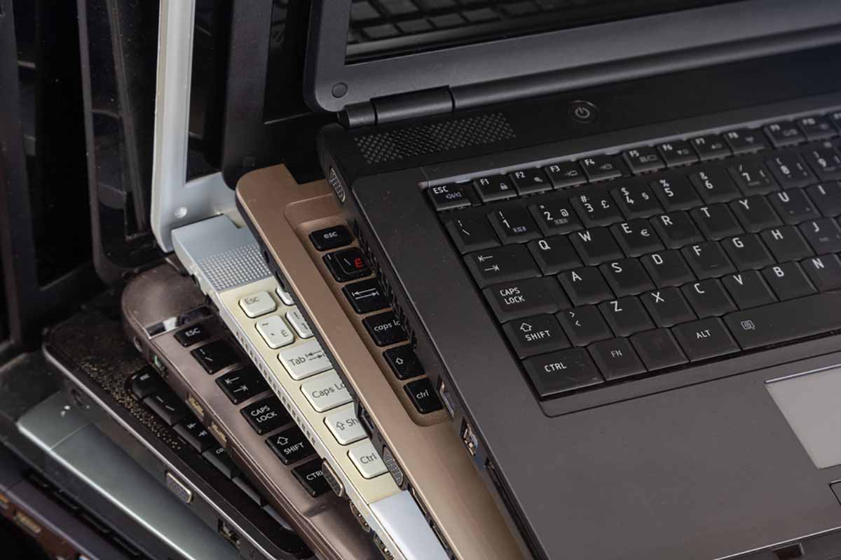 Old laptops stacked together for recycling.