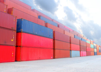 Shipping containers stacked in a logistic yard.