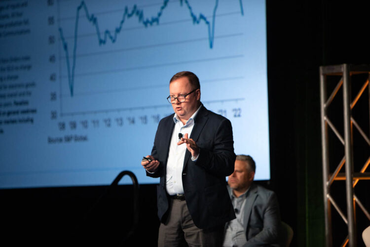 Joe Pickard speaks at the 2022 E-Scrap Conference with market graph on screen in the background.