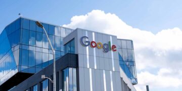 Google sign on company building with blue sky and clouds above.
