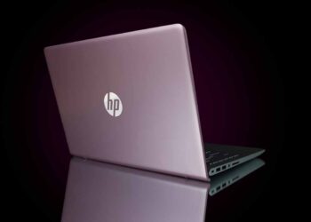 HP laptop on desk with black background.